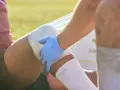 Medico con guanto blu fascia la gamba di un atleta, probabilmente per una lesione adduttore.