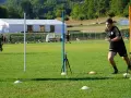 Allenatore osserva un atleta eseguire un test di agilità, con coni e paletti disposti sul campo per il **yoyo test tabella**.