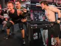 Atleti in pieno sforzo: uno esegue uno squat con bilanciere, l'altro un dip alle parallele. Questo è il vero training, cos'è la forza.