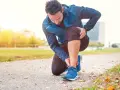 Uomo in ginocchio sul sentiero, si tocca la caviglia con espressione sofferente, forse una distorsione tibio tarsica.