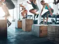 Allenamento di pliometria calcio: atleti saltano su box in palestra, migliorando esplosività e agilità.