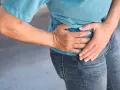 Uomo con mano sull'anca, soffre di coxalgia. Speranza di guarigione.