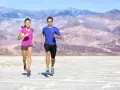 Coppia corre in un paesaggio desertico. Lei ha un livello aerobico basso, lui sembra più allenato.