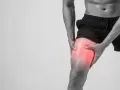 Uomo con dolore alla coscia, evidenziato in rosso, suggerisce microlesioni muscolari.