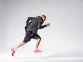 Atleta in corsa, concentrato sul suo obiettivo di aumentare il VO2max. Indossa abbigliamento sportivo nero e scarpe rosse.