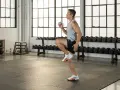 Uomo in palestra esegue un esercizio per i muscoli polpaccio, con manubri sullo sfondo.