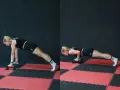 Donna esegue push up con maniglie, concentrata sul movimento.