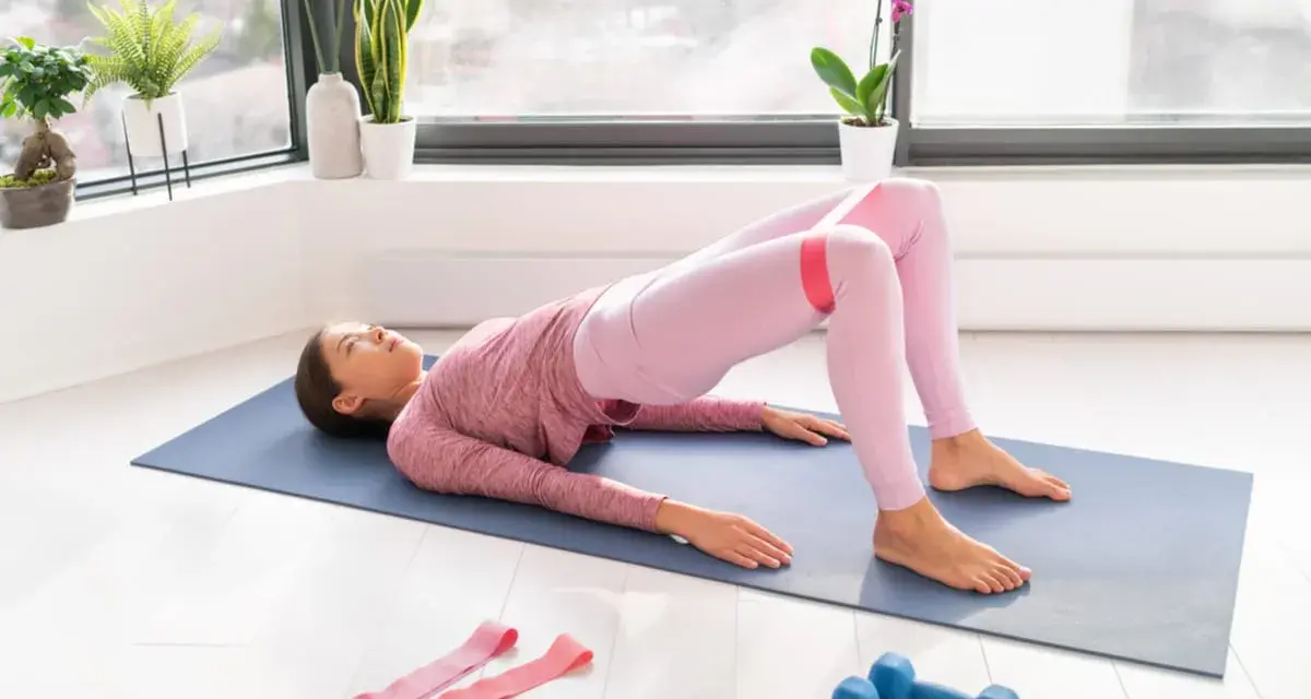 Donna esegue hip thrust con elastico per i glutei, scoprendo i benefici di un allenamento mirato per tonificare e rafforzare.