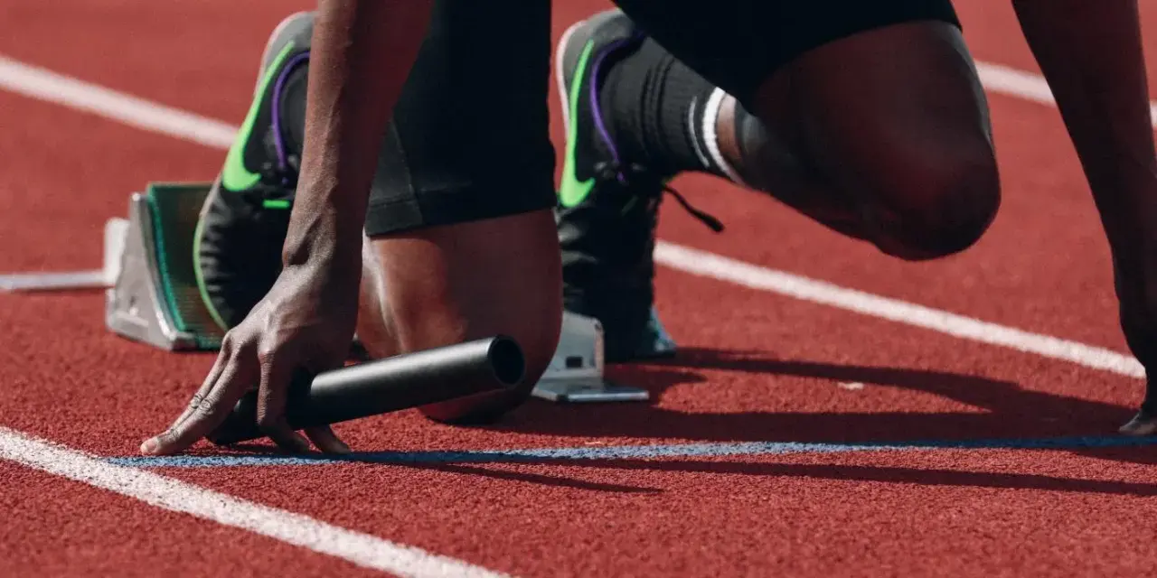 Atleta in posizione di partenza, pronto a scattare. La concentrazione è massima, un vero allenamento mentale prima della gara.