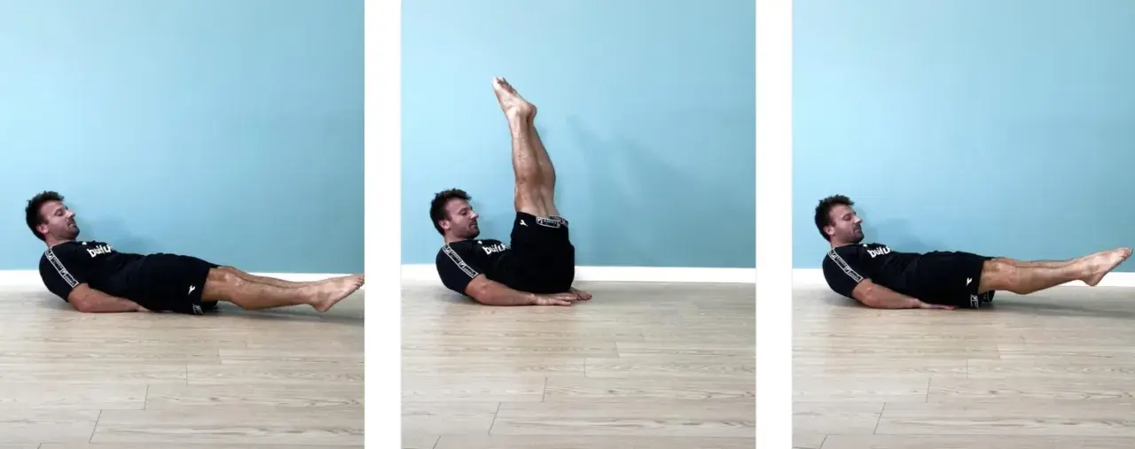 Uomo esegue leg raise a terra gambe tese, sollevando le gambe dritte verso l'alto e poi abbassandole lentamente.