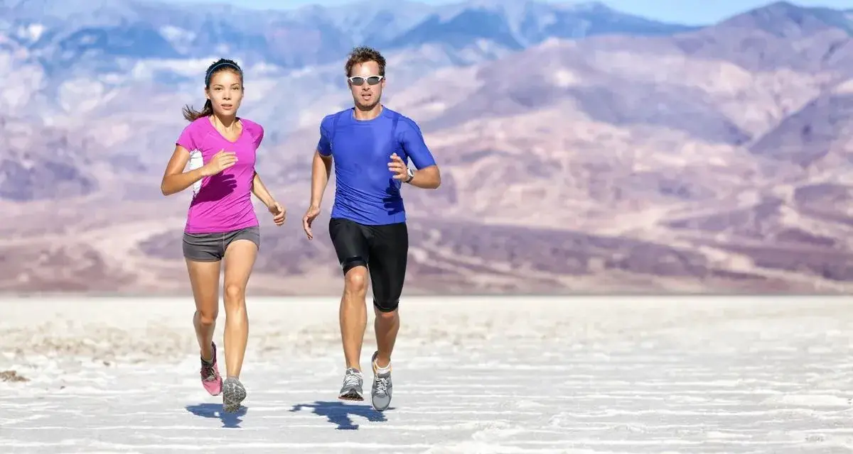 Coppia corre in un paesaggio desertico. Lei ha un livello aerobico basso, lui sembra più allenato.
