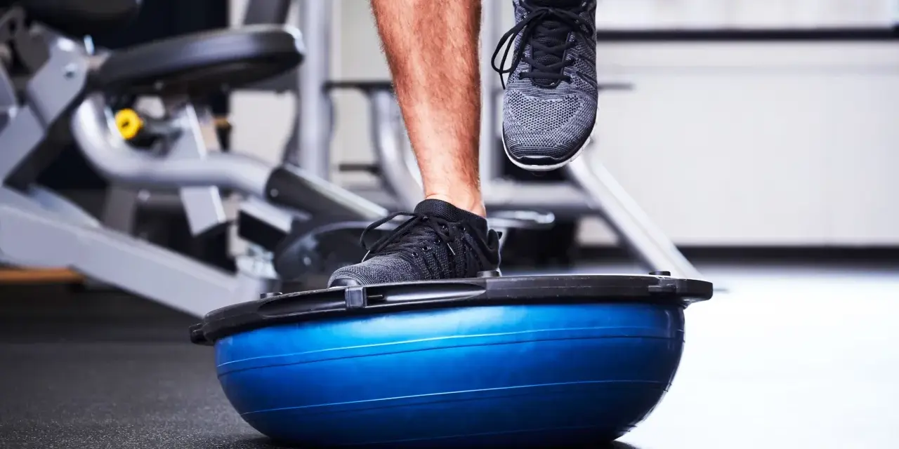 Allenamento in palestra con un piede su una palla BOSU per migliorare la stabilità dell'articolazione talocrurale.