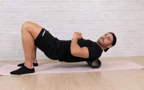 Uomo con foam roller sotto la schiena, per alleviare il dolore gambe dopo allenamento.