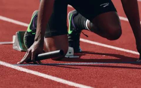 Atleta in posizione di partenza, pronto a scattare. La concentrazione è massima, un vero allenamento mentale prima della gara.