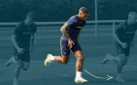 Three soccer players in training gear running on a field, with the central player in focus.