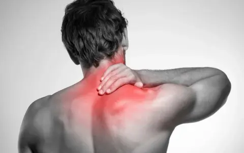 Uomo con mano sul collo, evidenziato in rosso il dolore ai muscoli del collo e delle spalle.