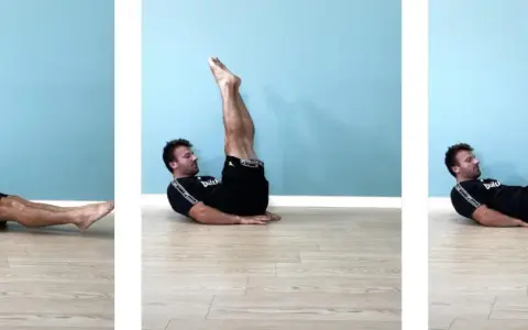 Uomo esegue leg raise a terra gambe tese, sollevando le gambe dritte verso l'alto e poi abbassandole lentamente.