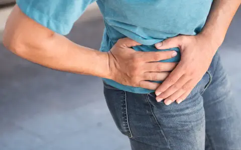 Uomo con mano sull'anca, soffre di coxalgia. Speranza di guarigione.