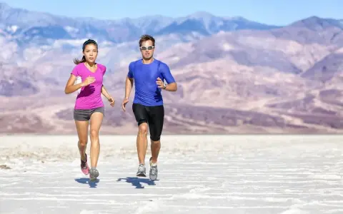 Coppia corre in un paesaggio desertico. Lei ha un livello aerobico basso, lui sembra più allenato.