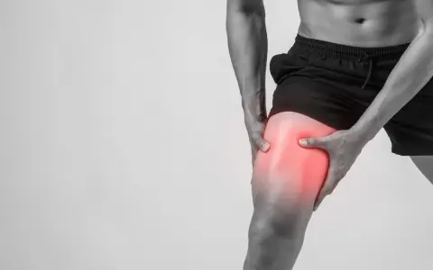 Uomo con dolore alla coscia, evidenziato in rosso, suggerisce microlesioni muscolari.