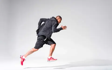 Atleta in corsa, concentrato sul suo obiettivo di aumentare il VO2max. Indossa abbigliamento sportivo nero e scarpe rosse.