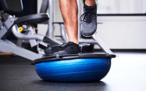 Allenamento in palestra con un piede su una palla BOSU per migliorare la stabilità dell'articolazione talocrurale.