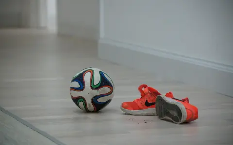 Pallone da futsal e scarpe arancioni su parquet. Pronto per una partita, ma cos'è il futsal? Uno sport veloce e tecnico.