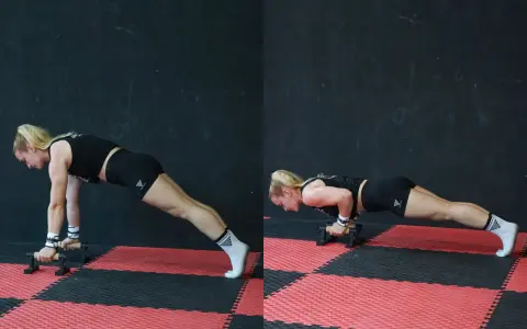 Donna esegue push up con maniglie, concentrata sul movimento.