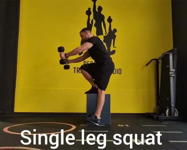 Uomo esegue squat monopodalico con manubri, allenamento per la forza e l'equilibrio.