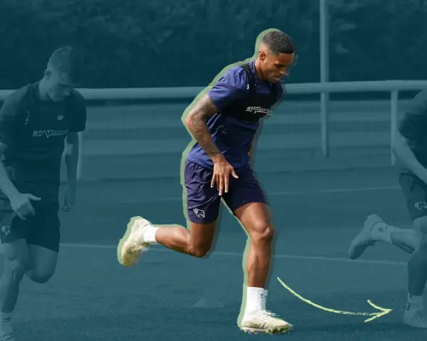 Three soccer players in training gear running on a field, with the central player in focus.