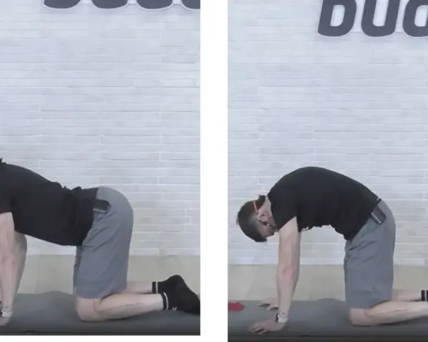 Uomo in posizione quadrupede, esegue stretching pre allenamento pesi: inarcamento schiena verso l'alto e poi verso il basso.