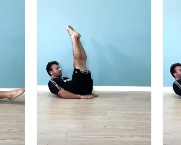 Uomo esegue leg raise a terra gambe tese, sollevando le gambe dritte verso l'alto e poi abbassandole lentamente.