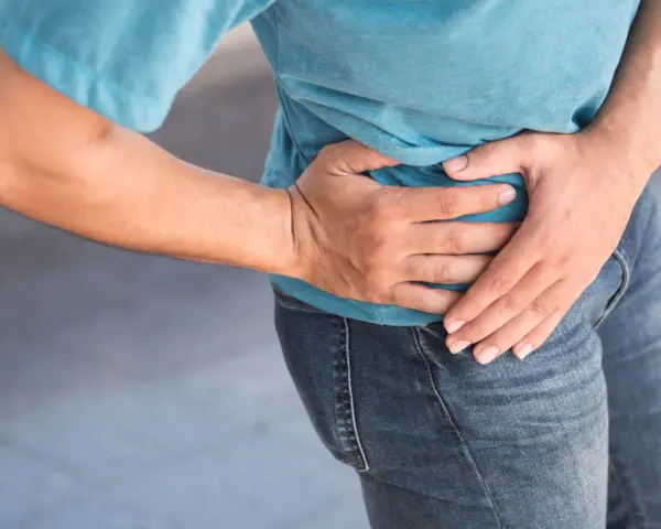 Uomo con mano sull'anca, soffre di coxalgia. Speranza di guarigione.