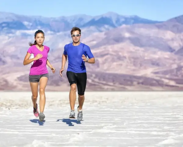 Coppia corre in un paesaggio desertico. Lei ha un livello aerobico basso, lui sembra più allenato.