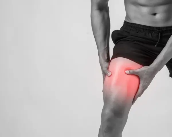 Uomo con dolore alla coscia, evidenziato in rosso, suggerisce microlesioni muscolari.
