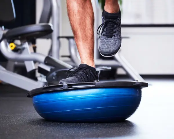 Allenamento in palestra con un piede su una palla BOSU per migliorare la stabilità dell'articolazione talocrurale.