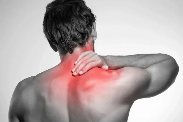 Uomo con mano sul collo, evidenziato in rosso il dolore ai muscoli del collo e delle spalle.
