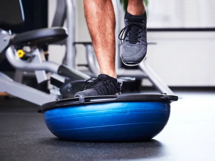 Allenamento in palestra con un piede su una palla BOSU per migliorare la stabilità dell'articolazione talocrurale.