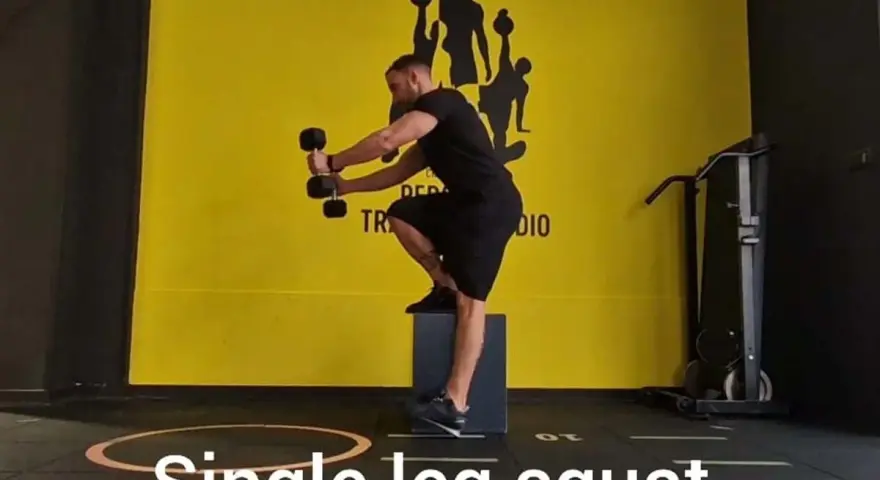 Uomo esegue squat monopodalico con manubri, allenamento per la forza e l'equilibrio.