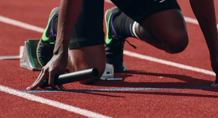Atleta in posizione di partenza, pronto a scattare. La concentrazione è massima, un vero allenamento mentale prima della gara.