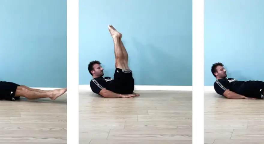Uomo esegue leg raise a terra gambe tese, sollevando le gambe dritte verso l'alto e poi abbassandole lentamente.