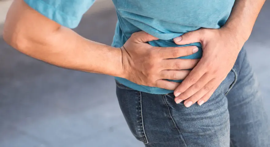 Uomo con mano sull'anca, soffre di coxalgia. Speranza di guarigione.
