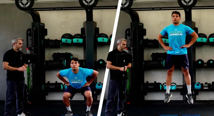 Uomo esegue un countermovement jump in palestra, guidato da un istruttore.