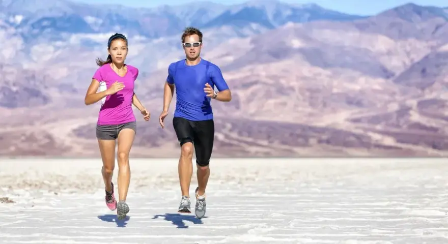 Coppia corre in un paesaggio desertico. Lei ha un livello aerobico basso, lui sembra più allenato.