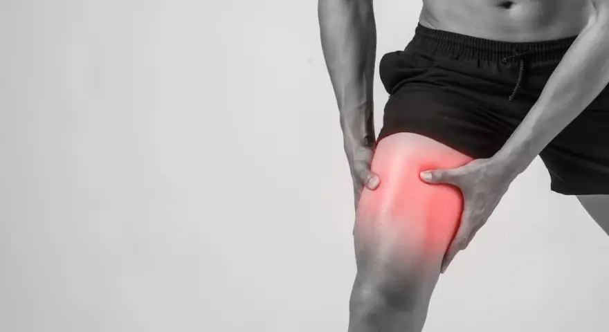 Uomo con dolore alla coscia, evidenziato in rosso, suggerisce microlesioni muscolari.