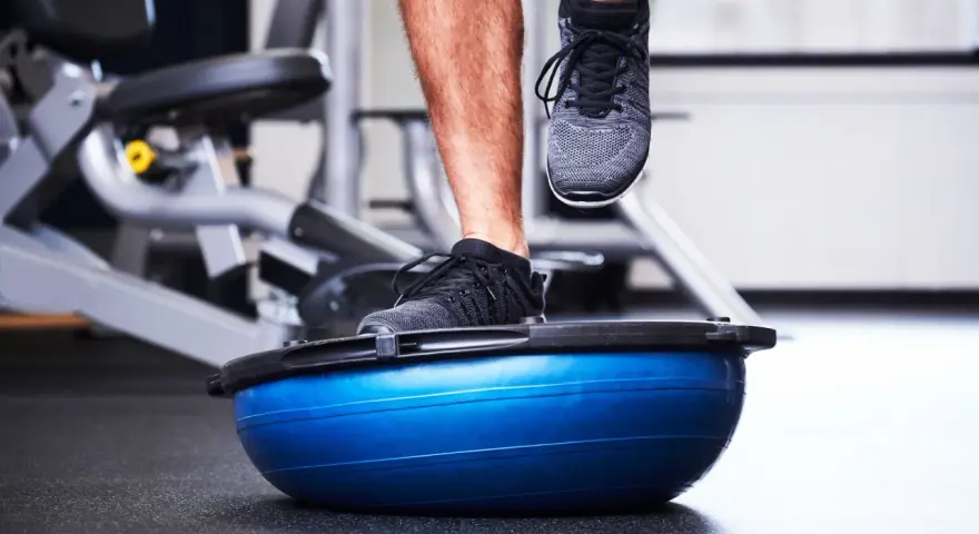 Allenamento in palestra con un piede su una palla BOSU per migliorare la stabilità dell'articolazione talocrurale.