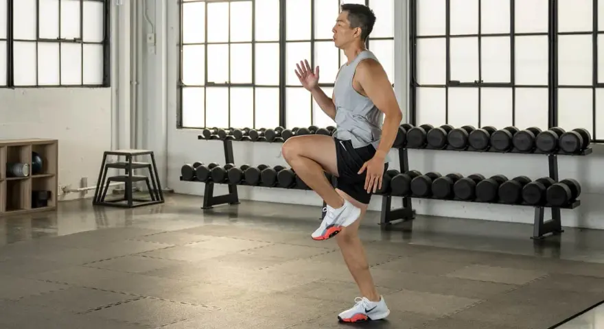 Uomo in palestra esegue un esercizio per i muscoli polpaccio, con manubri sullo sfondo.