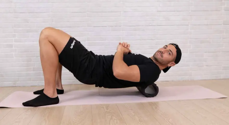 Uomo con foam roller sotto la schiena, mostrando cosa succede ai muscoli dopo l'allenamento. Recupero muscolare.