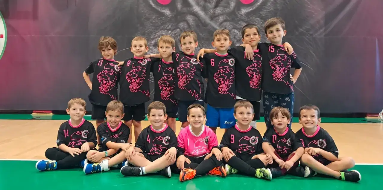 Squadra di bambini sorridenti in tenuta da calcio con leoni rosa. Un gruppo pronto per divertenti partite a tema calcio.