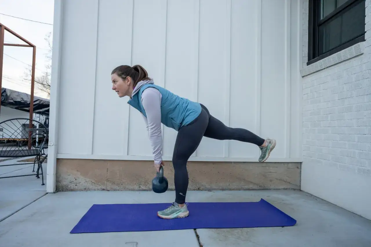 Donna esegue un esercizio monopodalico con kettlebell, migliorando equilibrio e forza.